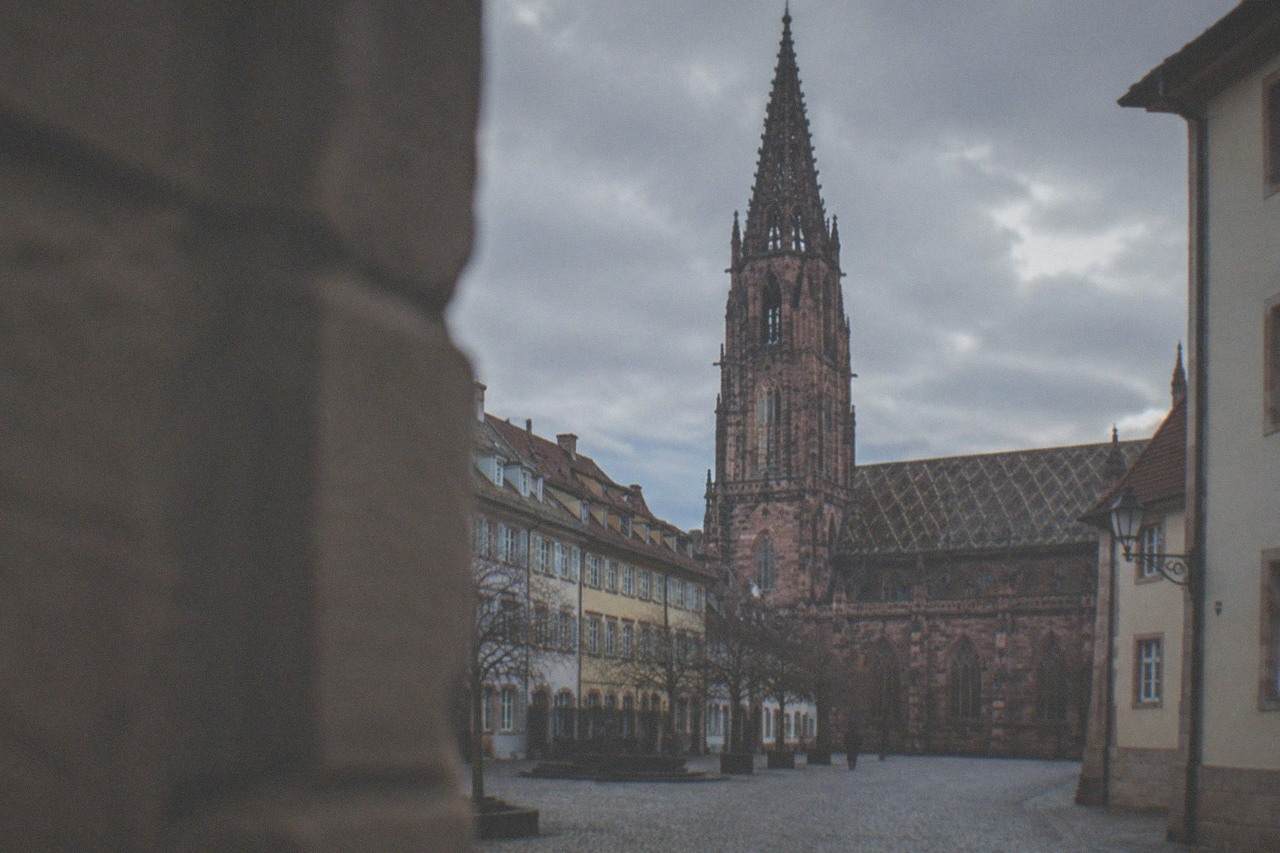 Empty cobbled street in Freiburg old town with the minster tower rising above the rooftops in evening light