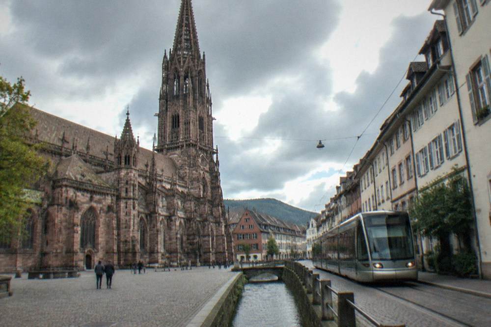 Freiburg tram moving through a narrow old town street with a canal of running water beside the track