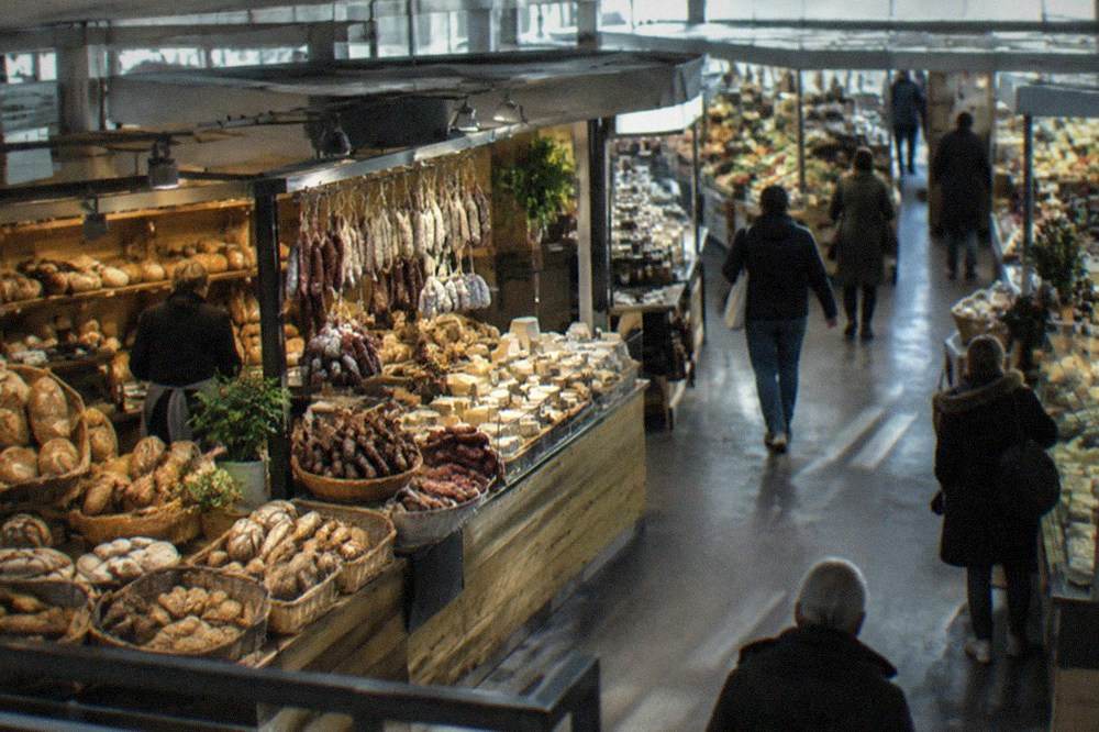 Münstermarkt stall with fresh bread, sausage and local cheese arranged in baskets.
