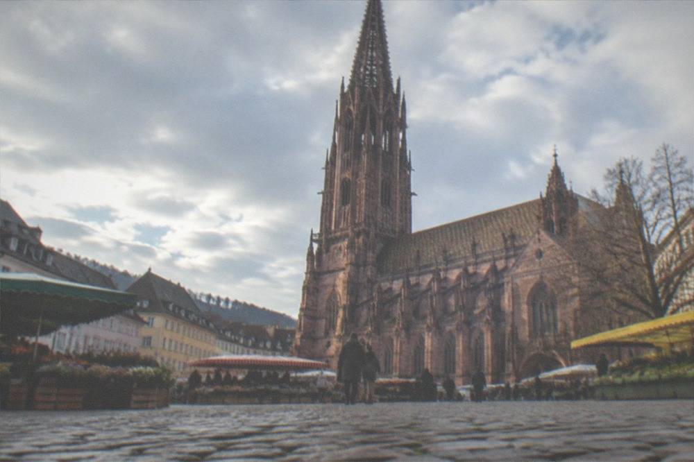 The red sandstone minster tower above the market square with colorful stalls below