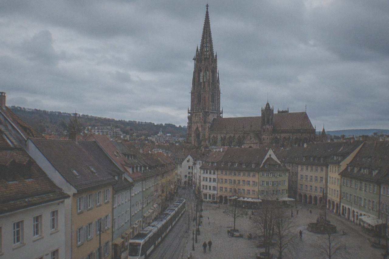 A Freiburg tram passing through the old town with the minster spire behind the rooftops