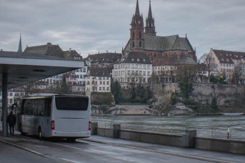 A regional bus parked at an airport terminal curb on a clear morning