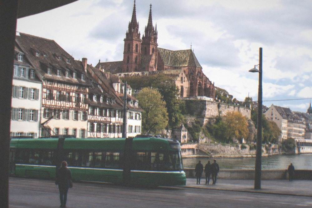 A station forecourt with a tram passing in front of old buildings