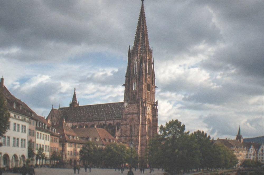 Freiburg minster with red sandstone tower rising above rooftop level of the old town