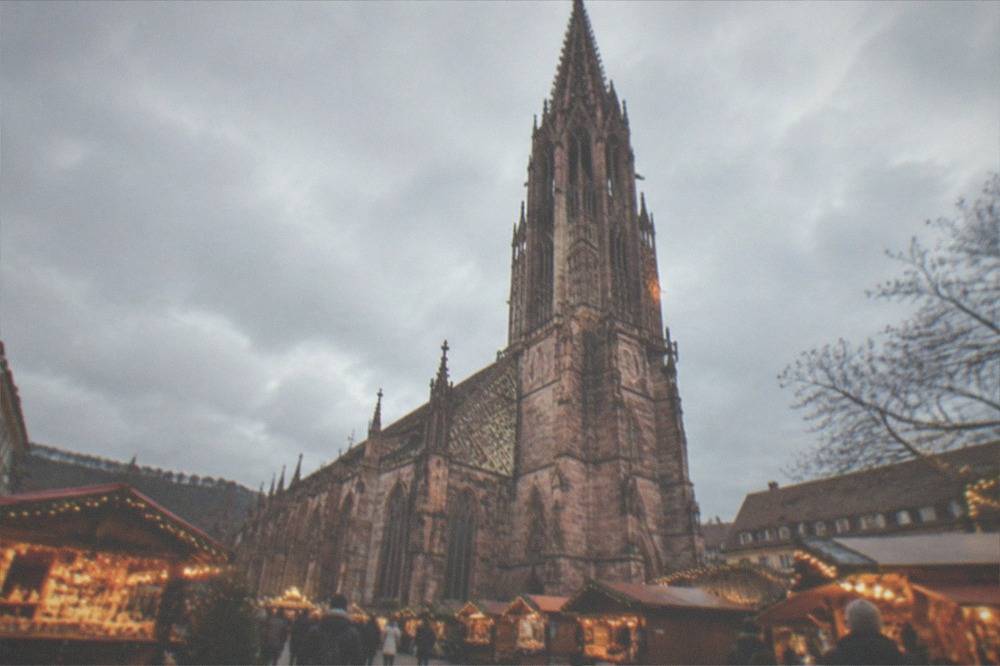 Festively lit wooden market stalls on a square in Freiburg old town at dusk