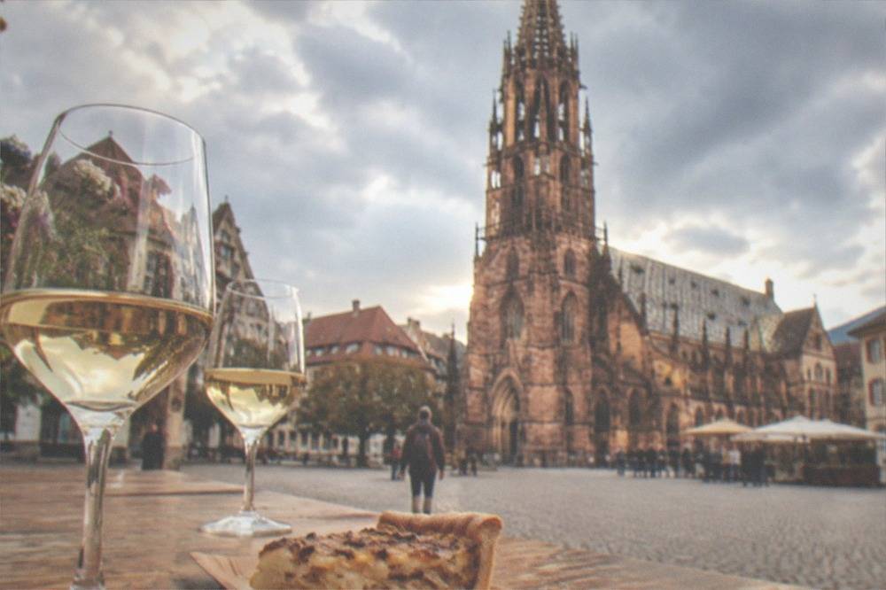 Wine glasses and a slice of onion tart on a wooden market table