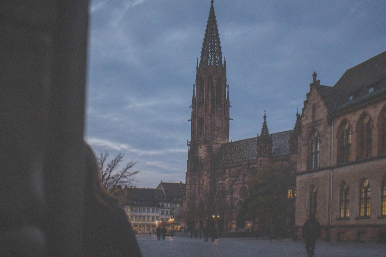 Historic university building facade with warm stone walls and tall arched windows in Freiburg