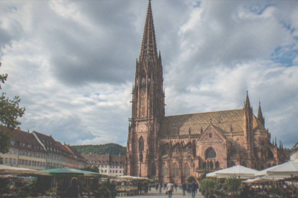 Sunlit Freiburg market square with stalls and cafe tables in warm weather