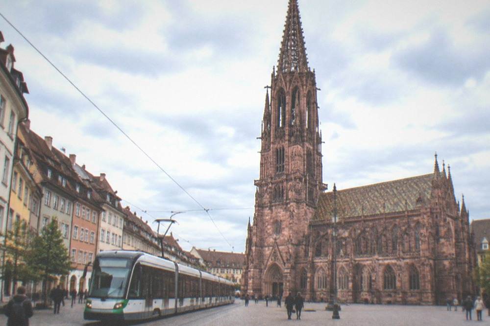 Freiburg tram crossing a street beside the old town buildings