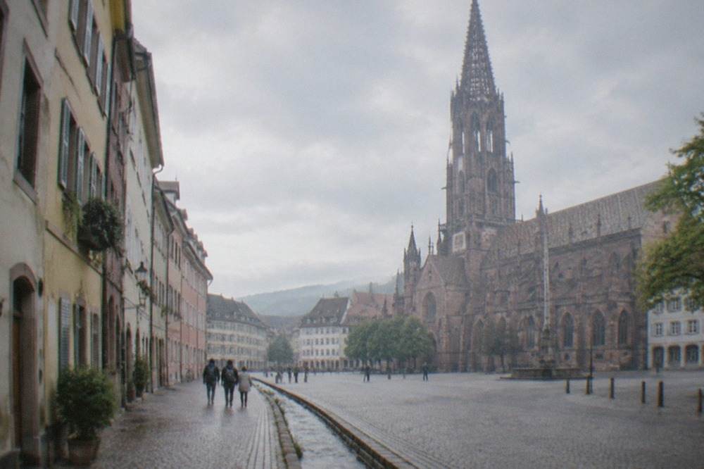 Cobblestone street with pastel facades and a small stream running along the gutter in central Freiburg