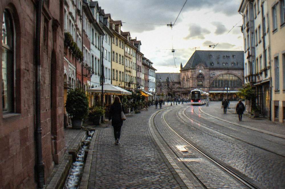 Modern hotel street with tram tracks running past a railway station entrance in the evening