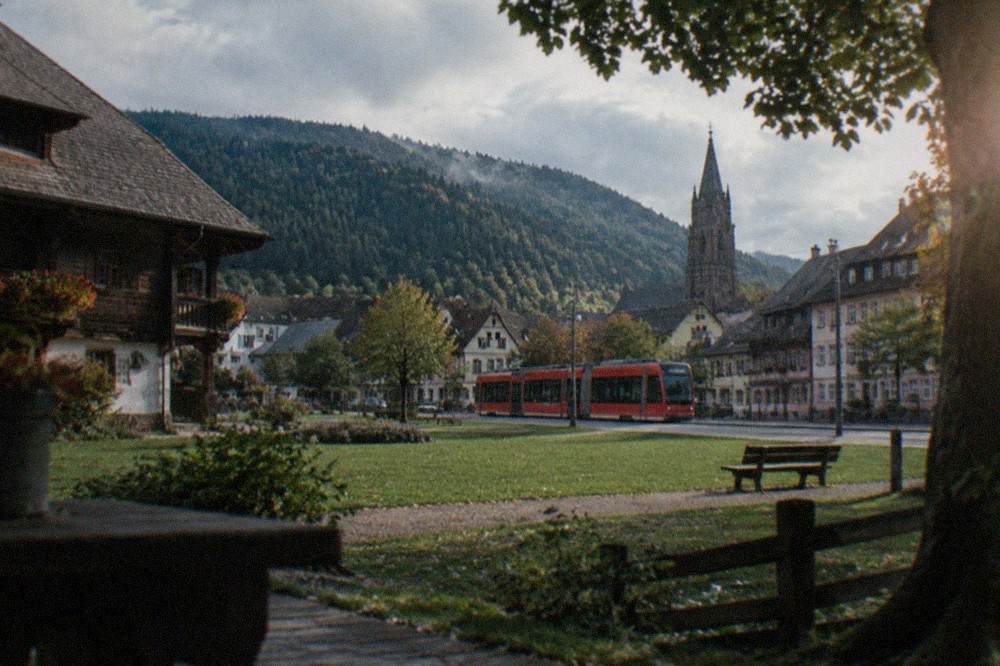 Freiburg's red tram running past old town facades with the cathedral tower behind