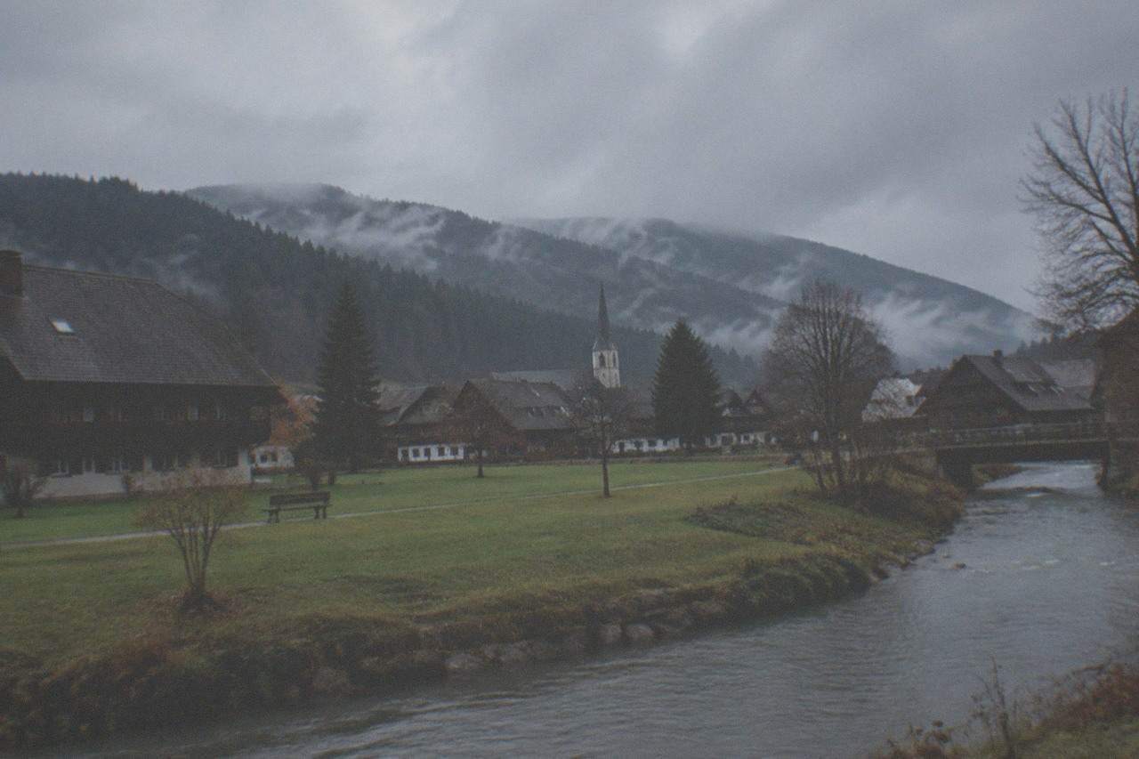 Morning mist over dark forested hills with a small village church spire in a valley