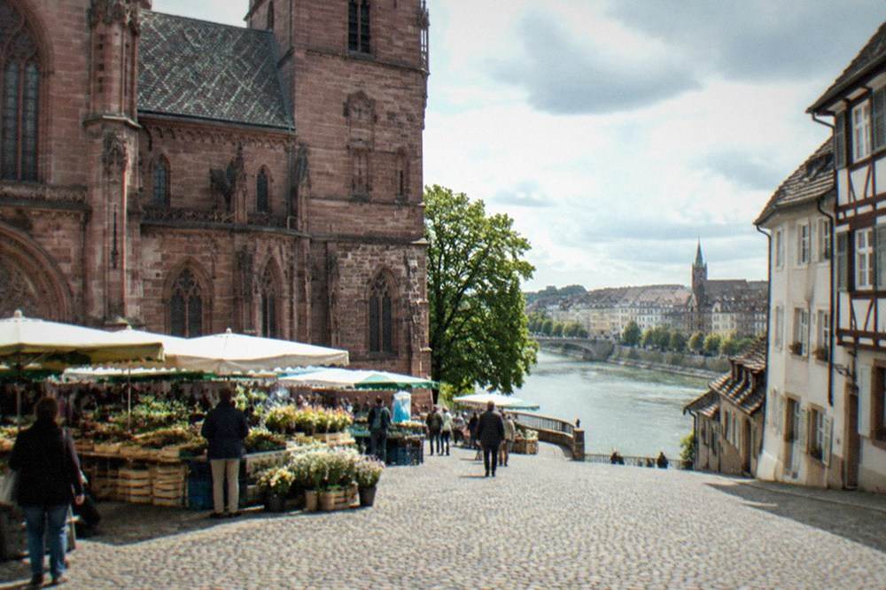 Cobbled square with market stalls in front of a red sandstone gothic cathedral
