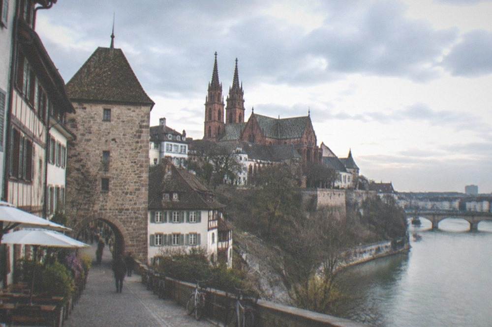 Historic stone gate tower above a pedestrian street with cafés and bicycles