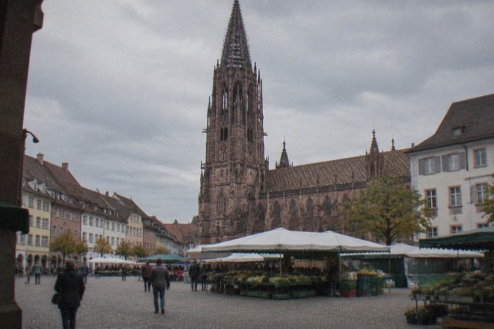 Cobbled Freiburg old town square with the gothic minster tower behind market stalls