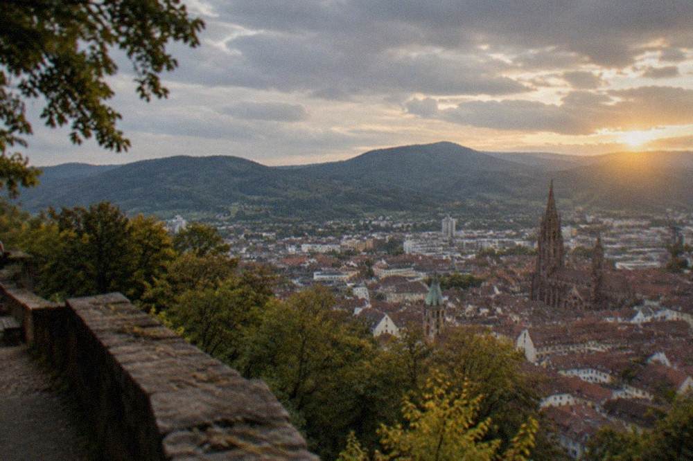View from the Schlossberg over Freiburg rooftops toward the Black Forest hills at late afternoon