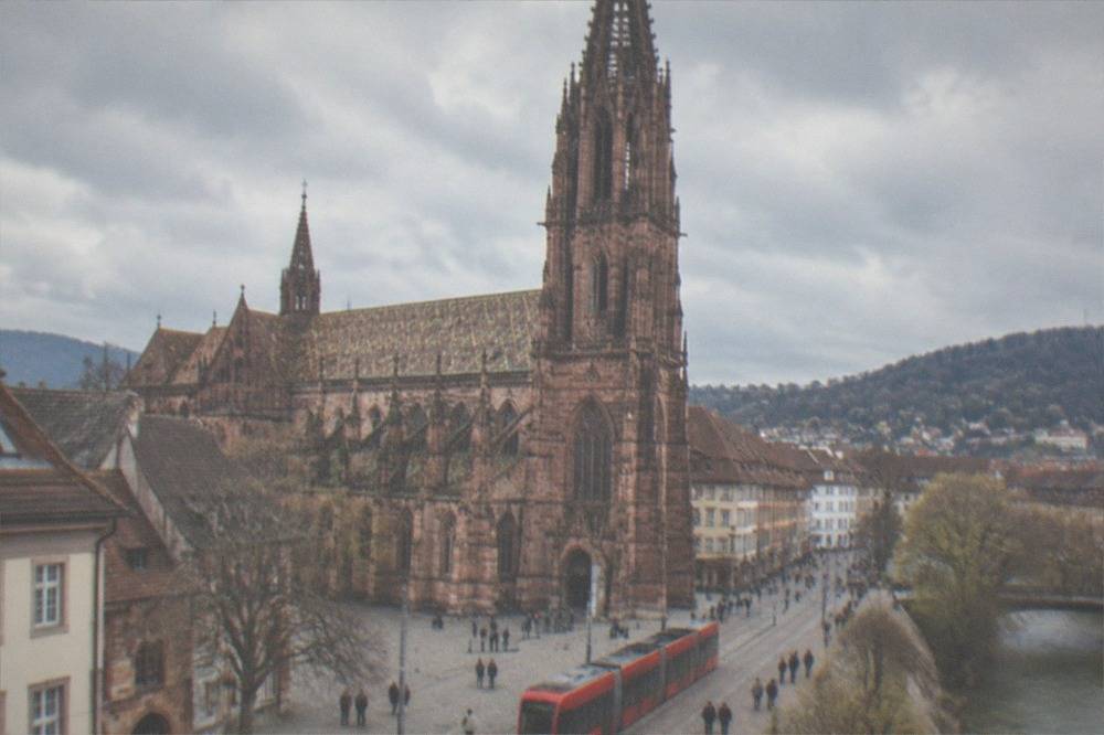 Red Freiburg tram moving through a pedestrian street with people walking alongside