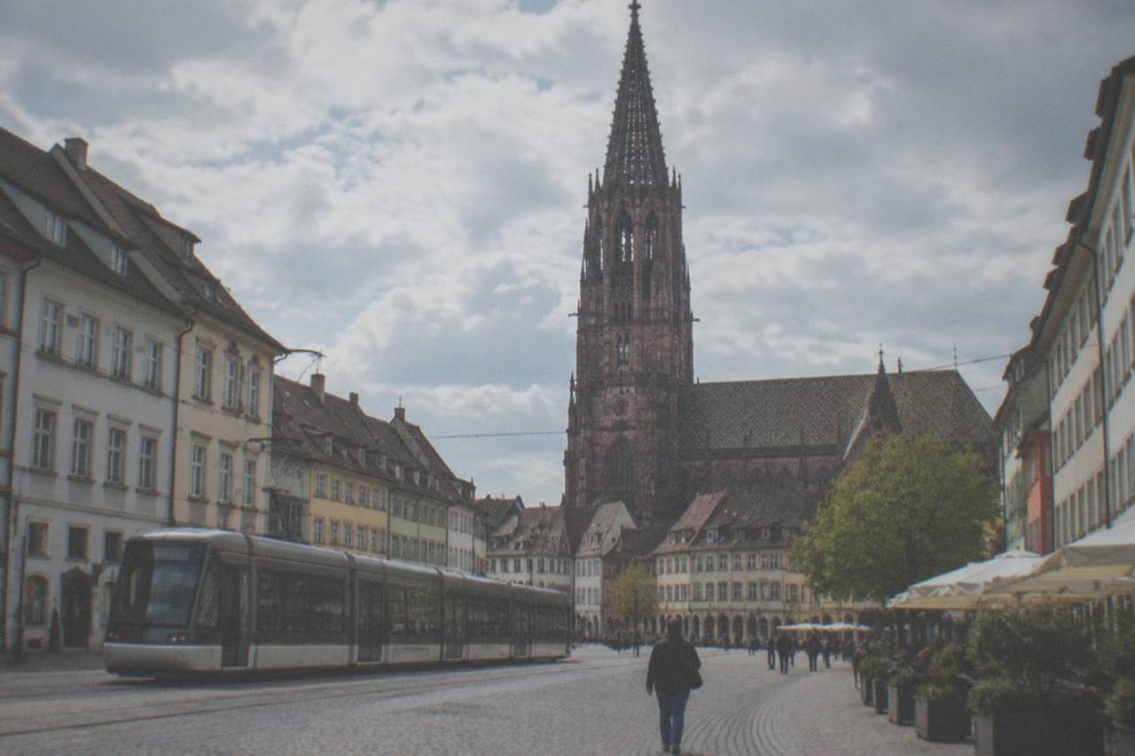 Freiburg old street with a tram and the cathedral tower behind the rooftops