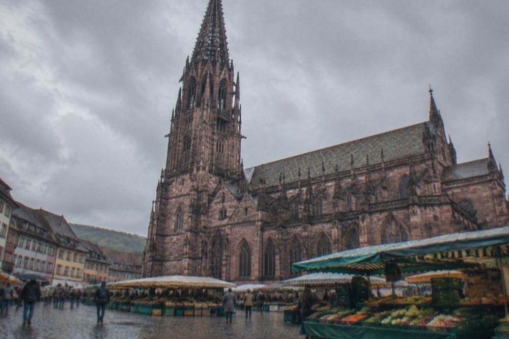 Market stalls with fresh produce arrayed in front of the gothic Freiburg Minster
