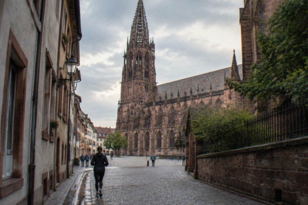 A narrow old town lane in Freiburg with a small water gutter running along the kerb