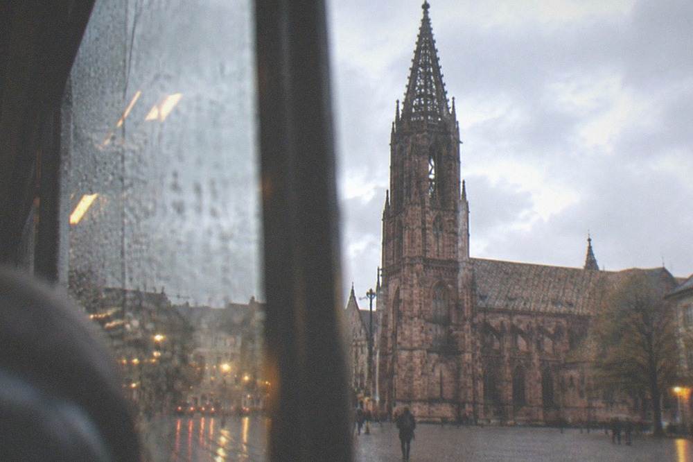 Raindrops on a tram window with blurred Freiburg street lights beyond the glass