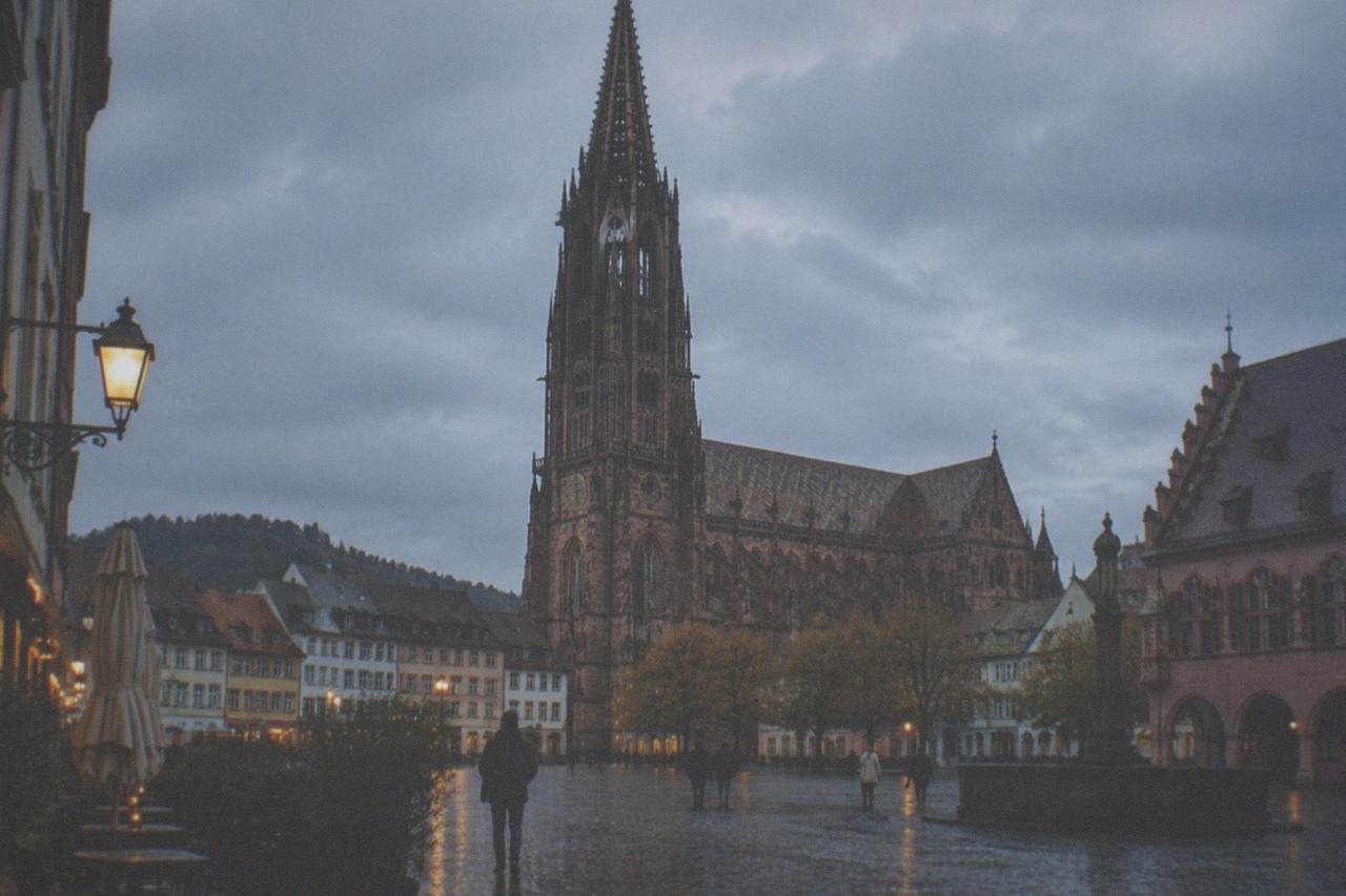 Wet cobblestone street in Freiburg old town with the minster tower rising above rooftops in gray light